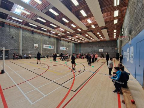 Group of children in a hall participating in sports skill and games sessions